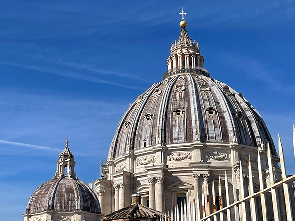 The domed top of St. Peters Basilica in Rome stands out against a bright blue sky.